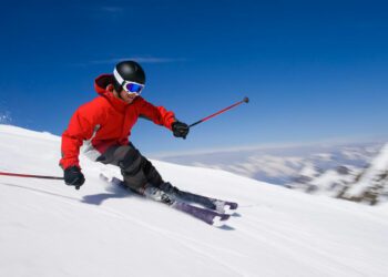 Narciarz w czerwonym ubraniu na stoku narciarskim. - Traveligo Blog