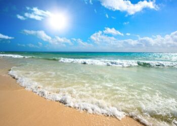 Piaszczysta plaża, turkusowe morze, błękitne niebo z białymi chmurami - Traveligo Blog