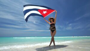 Kobieta w kostiumie kąpielowym macha kubańską flagą na plaży - Traveligo Blog