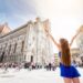 Duża historyczna budowla, ludzie spacerujący po placu. - Traveligo Blog