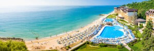 Piękna, wzbogacona zielenią plaża z błękitnym basenem, górskimi krajobrazami i zadbanymi hotelami. Traveligo Blog