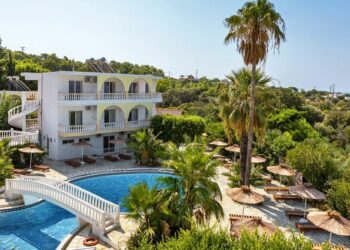 Biały budynek hotelowy z basenem i palmami. Traveligo Blog