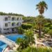 Biały budynek hotelowy z basenem i palmami. Traveligo Blog