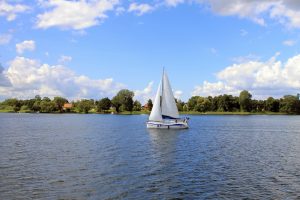 Żaglówka na wodzie otoczona drzewami - Traveligo Blog