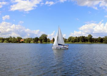Żaglówka na wodzie otoczona drzewami - Traveligo Blog