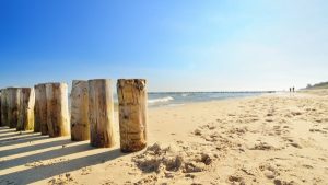 Drewniane pale na piaszczystej plaży nad Morzem Bałtyckim. Traveligo Blog