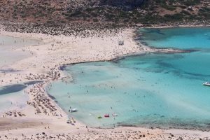 Tłum ludzi na plaży, turkusowa woda morska. Traveligo Blog