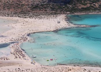 Tłum ludzi na plaży, turkusowa woda morska. Traveligo Blog