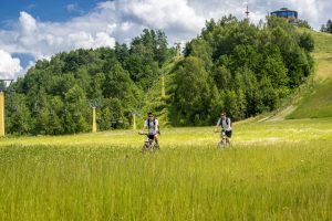Zielona, górska sceneria z jazydącymi na rowerach ludźmi - Traveligo Blog