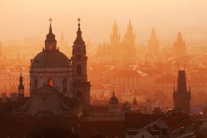 Panoramiczne ujęcie Pragi w ciepłej, pomarańczowej poświacie - Traveligo Blog