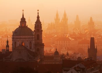 Panoramiczne ujęcie Pragi w ciepłej, pomarańczowej poświacie - Traveligo Blog