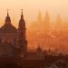 Panoramiczne ujęcie Pragi w ciepłej, pomarańczowej poświacie - Traveligo Blog