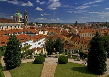 Piękny ogród Vrtbovski z krzewami i ścieżkami. Panorama Pragi ze strzelistymi wieżami. Traveligo Blog
