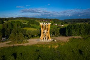 Wysoka drewniana wieża na tle zielonych wzgórz i lasu. Traveligo Blog