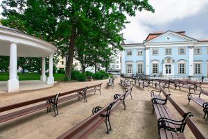 Zielone drzewa, zabytkowy budynek, ławki - Traveligo Blog
