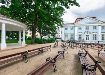 Zielone drzewa, zabytkowy budynek, ławki - Traveligo Blog