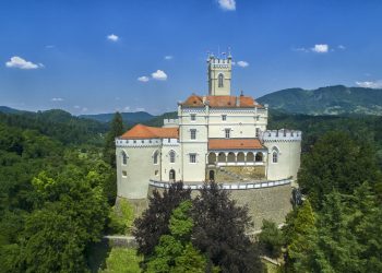 Zamek na wzgórzu otoczony drzewami. Traveligo Blog