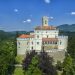 Zamek na wzgórzu otoczony drzewami. Traveligo Blog