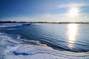 Zaśnieżona plaża nad rzeką przy wschodzącym słońcu. Traveligo Blog