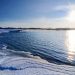 Zaśnieżona plaża nad rzeką przy wschodzącym słońcu. Traveligo Blog