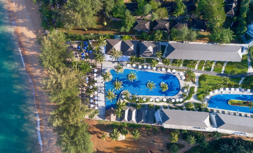Widok z lotu ptaka na X10 Khaolak Resort z dużym basenem, tropikalną roślinnością i piaszczystą plażą przy turkusowym morzu