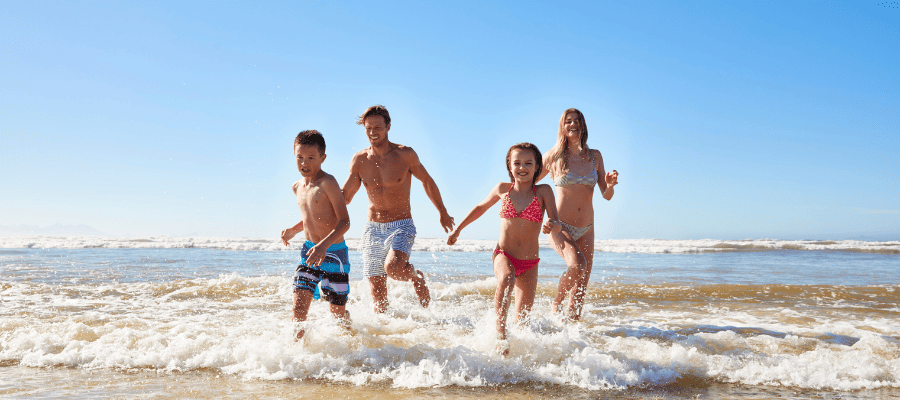 Rodzina biegnąca po plaży podczas wakacji w ciepłym kraju