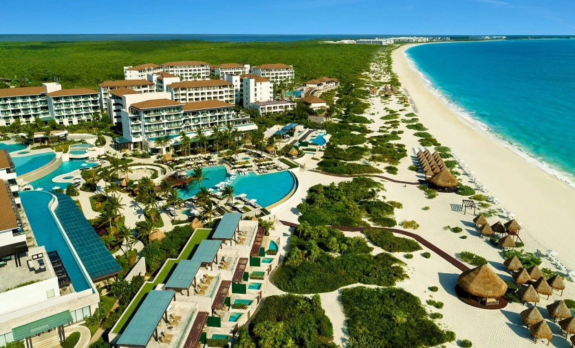 Panoramiczny widok na resort Dreams Playa Mujeres z rozległymi basenami, tropikalną roślinnością i szeroką, białą plażą nad turkusowym morzem