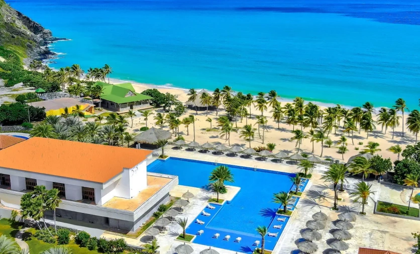 Widok na hotel Sunsol Ecoland z dużym basenem, palmami i szeroką piaszczystą plażą nad turkusowym morzem