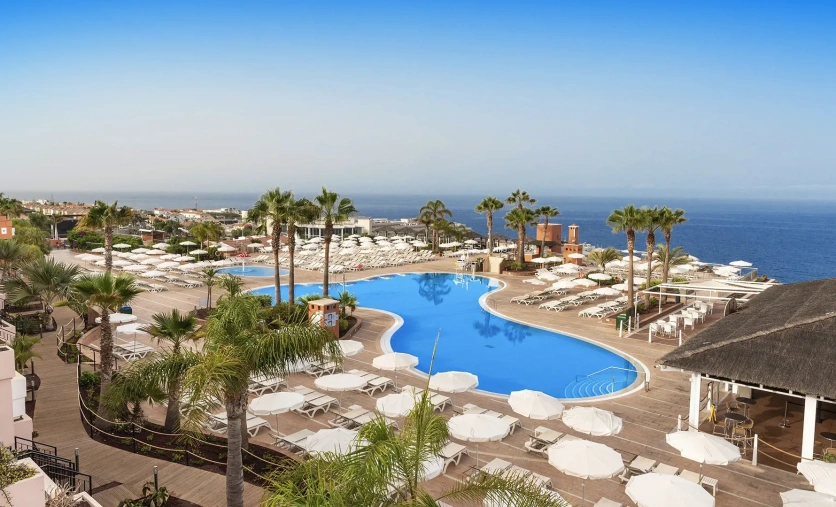 Panoramiczny widok na baseny, palmy i tarasy hotelu Landmar Costa Los Gigantes Family Resort z widokiem na ocean