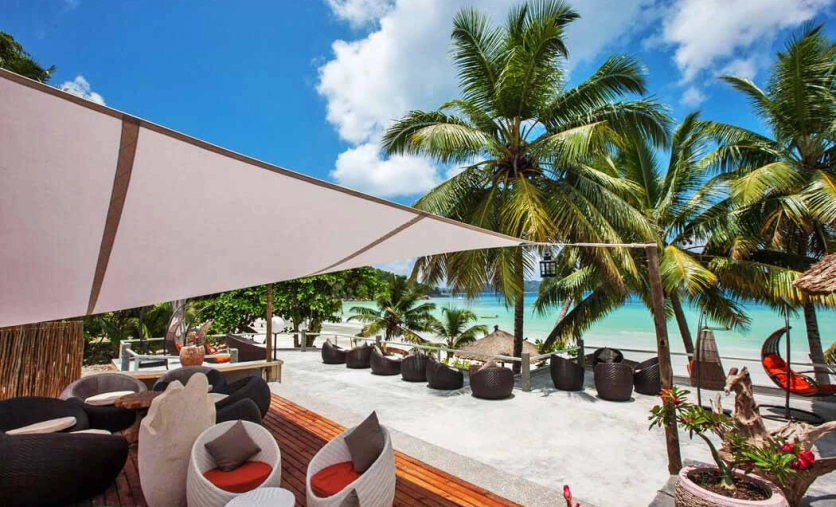 „Taras hotelu Le Duc de Praslin z widokiem na palmową plażę i turkusowe morze na Seszelach
