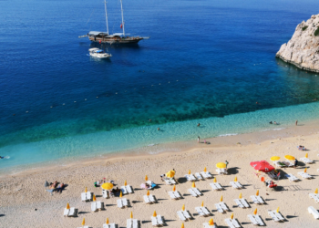 Riwiera Turecka – piaszczysta plaża z leżakami i parasolami przy krystalicznie czystym morzu, idealna na wakacje All Inclusive w Turcji.