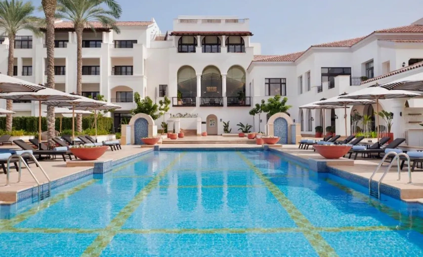 Luksusowy basen w hotelu Address Marassi Golf Resort w El Alamein z elegancką architekturą i leżakami