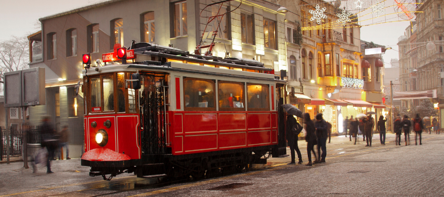 Zabytkowy czerwony tramwaj na ulicy Istiklal w Stambule o zmierzchu