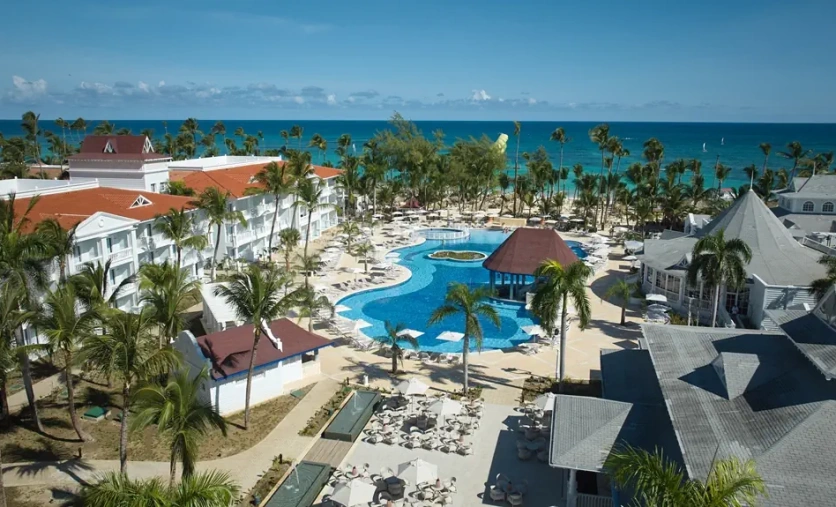 Hotel Bahia Principe Luxury Esmeralda w Punta Cana z basenem i palmami przy karaibskiej plaży